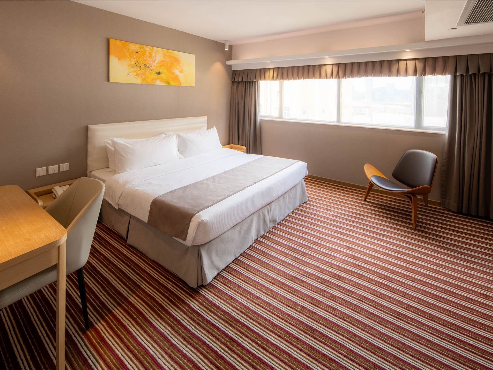 King-sized bedroom with a desk and abstract art in Executive Suite at Inn Hotel Macau, featuring affordable hotels in Macau