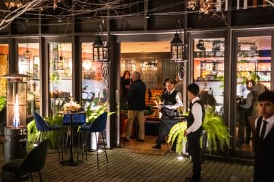 Restaurante Aubrey por la noche, con invitados y personal reunidos en la entrada del Hotel Aubrey