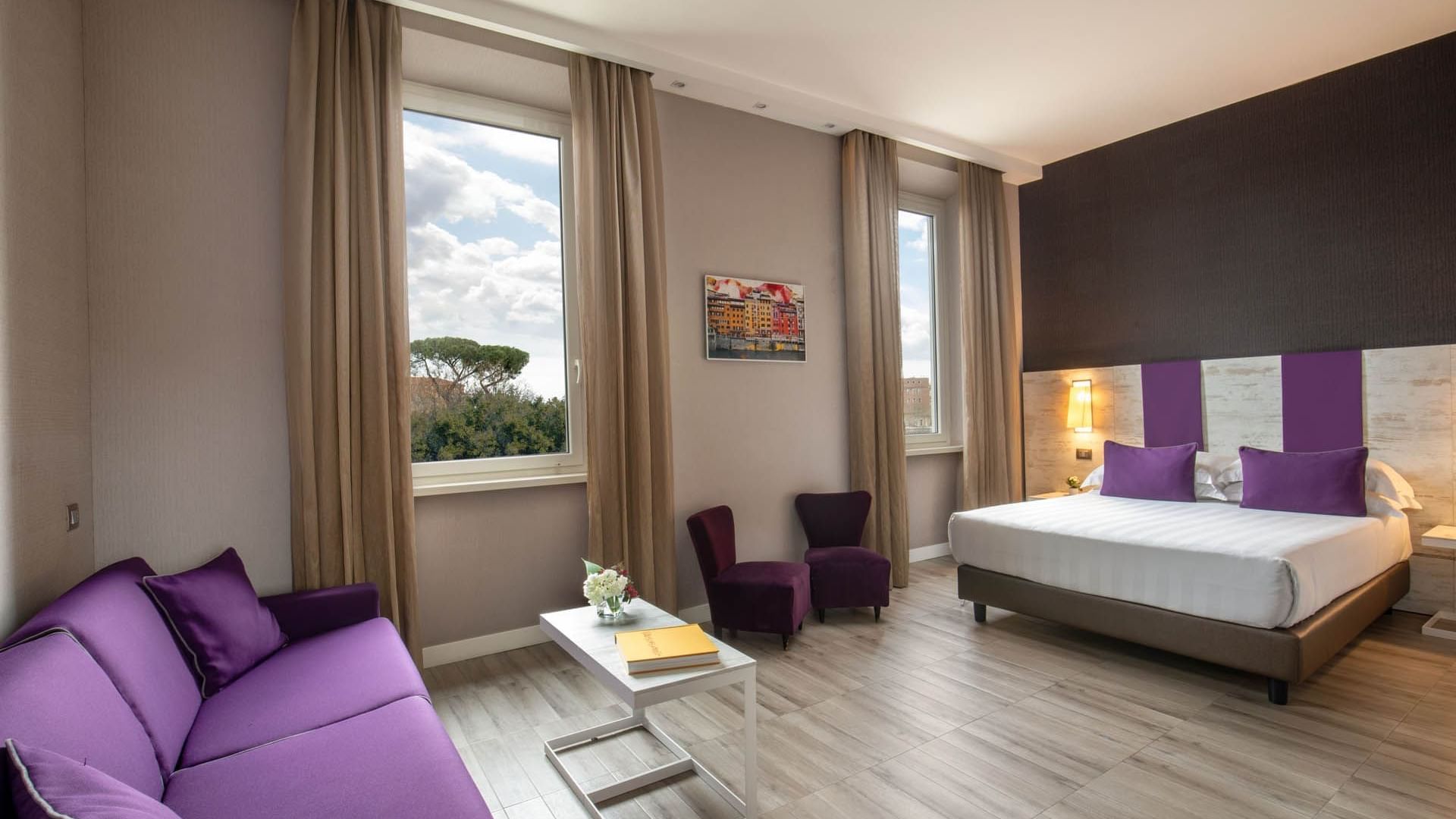 Cozy Family Room at The Guardian Hotel with purple accents, a comfy bed, a sofa, and large windows offering an outdoor view