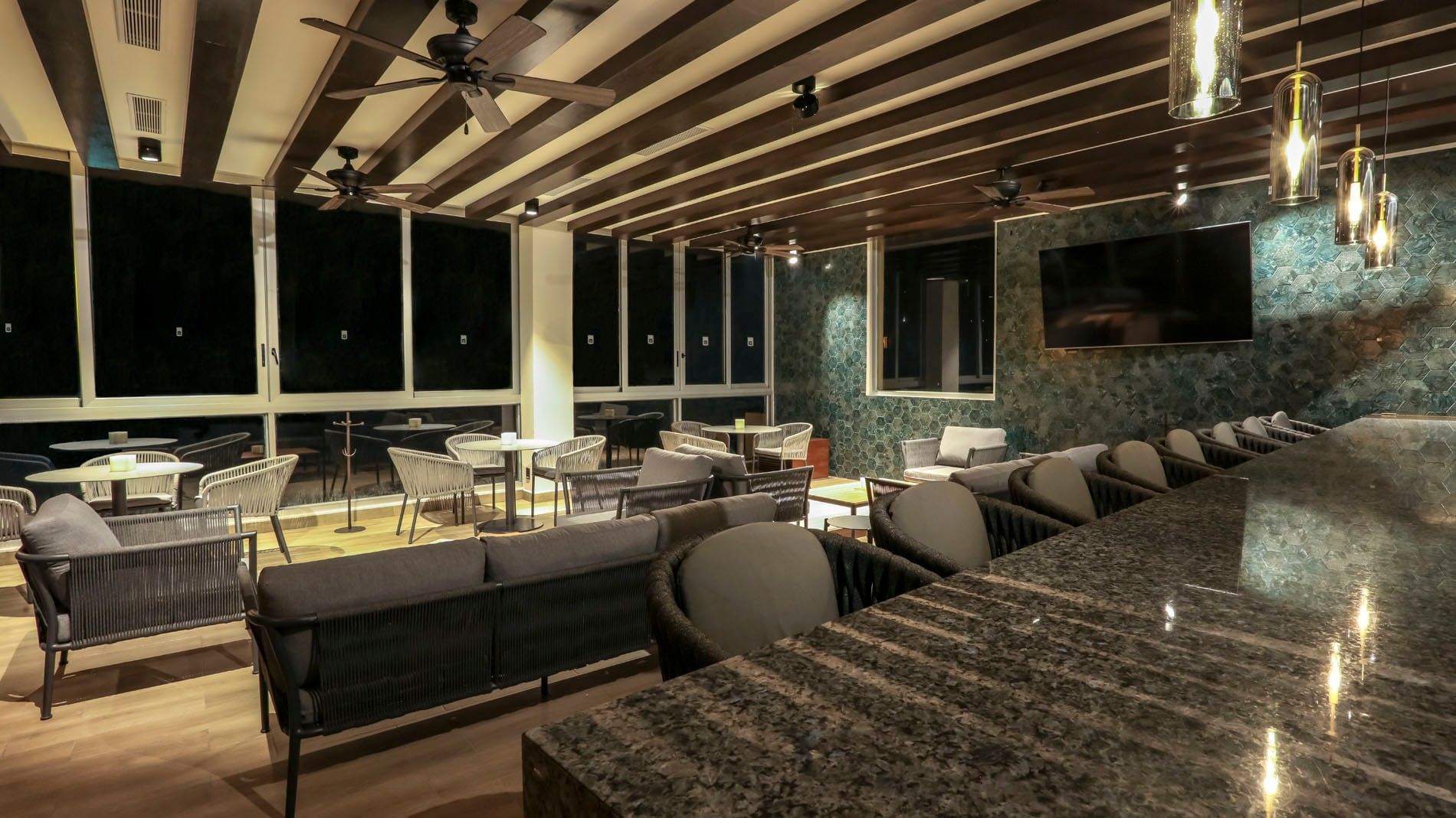 Bar Azul elegante de noche con barra de granito, techo de madera oscura y asientos acogedores en Camino Real Veracruz