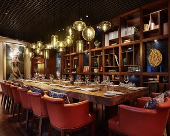 Square One interior featuring a long wooden table surrounded by plush chairs and pendant lighting at Park Hyatt Saigon