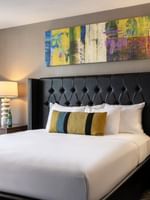 White bed with colorful pillows by modern lamps under a bright abstract painting in Queen Anne Suite at Warwick Seattle