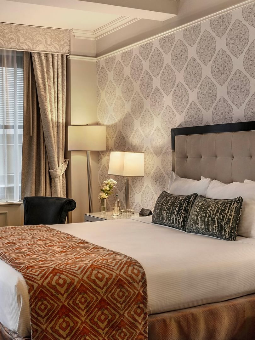Elegant Premier City View Suite with patterned wallpaper and a large bed at Warwick New York