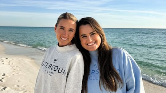 Two women wearing Watersound Club sweatshirts standing on a beach at Watersound Inn