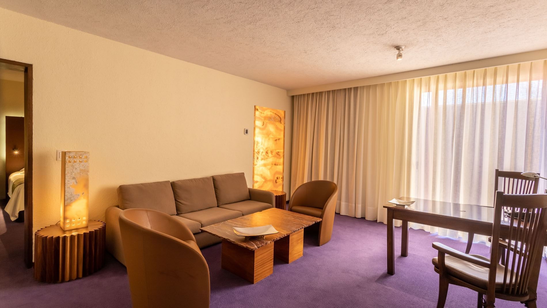 Sala en Suite Junior King con sillas de cuero, piso púrpura e iluminación cálida en Camino Real Polanco México