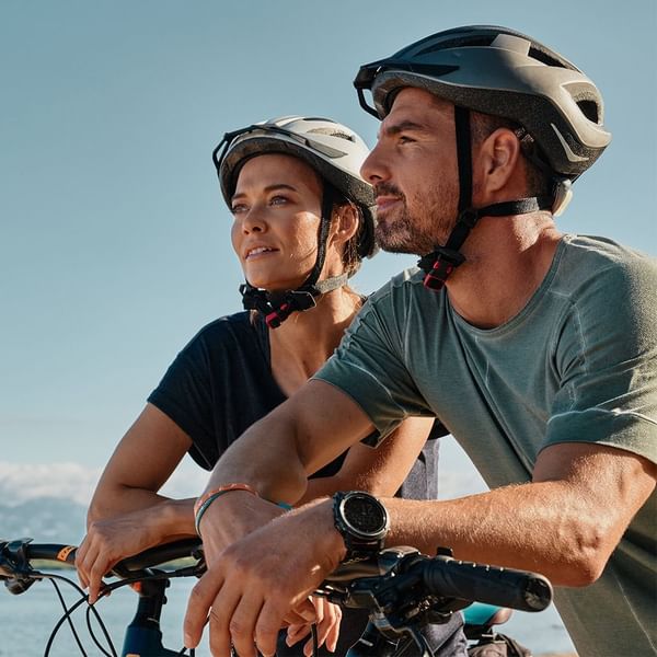 Two cyclists in helmets standing with a bike overlooking sea near Falkensteiner Resort Punta Skala