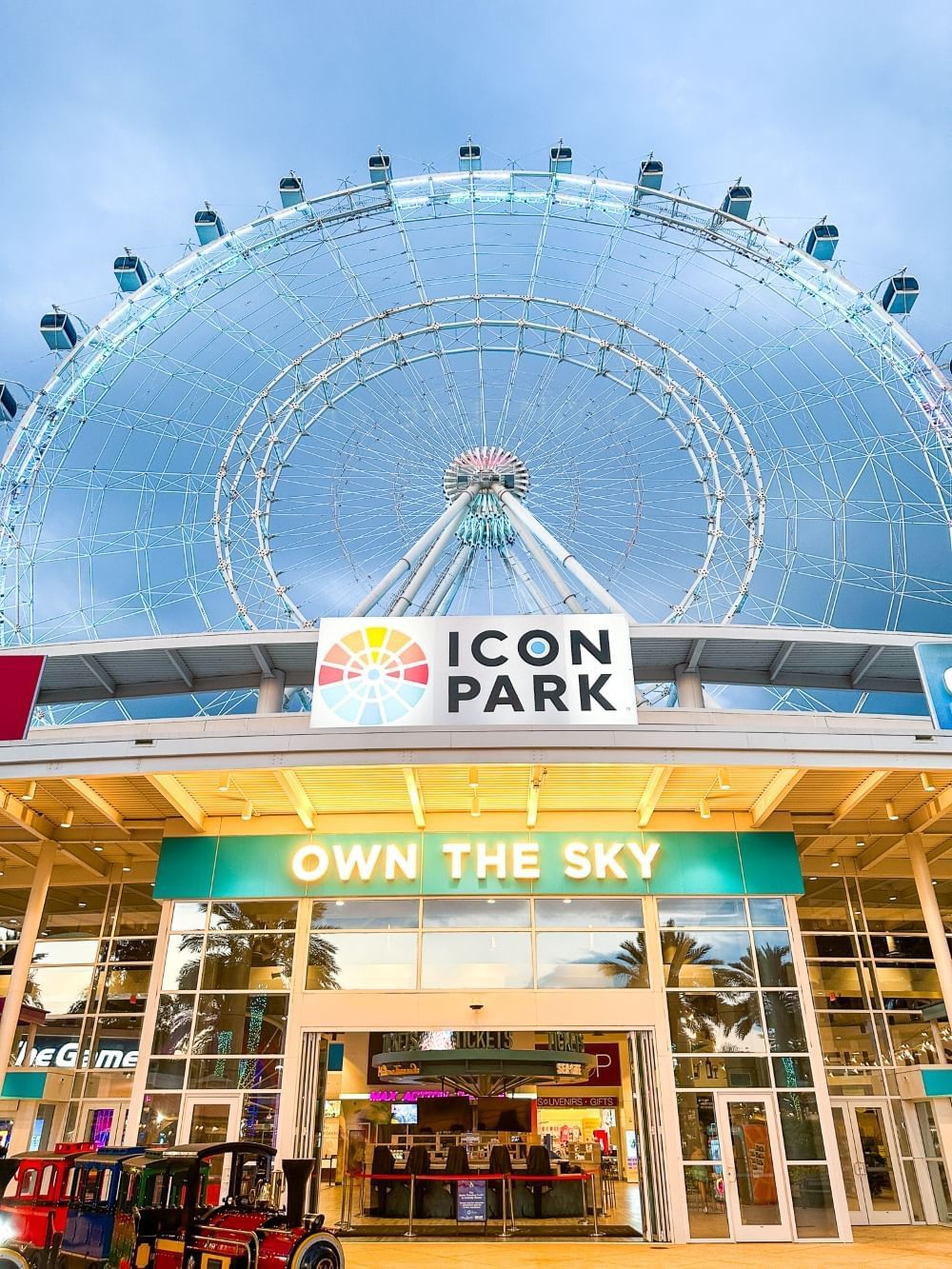A low angle shot of a building with a towering ferris wheel in the background.