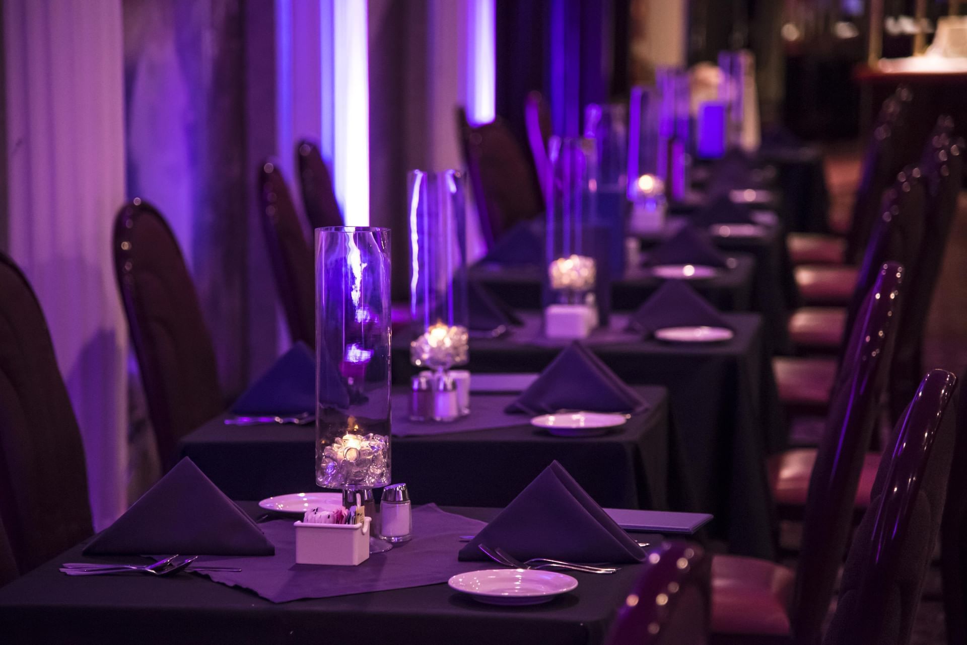 Well-arranged Dining Room with dark tables and purple lighting at Cove Pocono Resorts