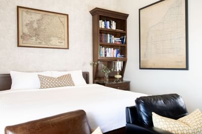 Bedroom interior with bookshelf, comfy chairs & King bed in King Premiere Library at Retro Suites Hotel