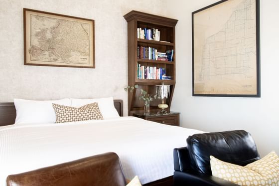 Bedroom interior with bookshelf, comfy chairs & King bed in King Premiere Library at Retro Suites Hotel