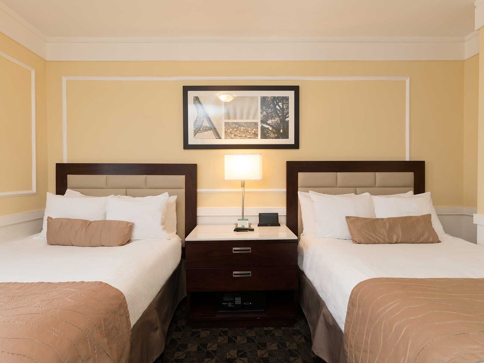 Two twin beds with white linens and brown comforters next to a nightstand at Pickwick San Francisco.