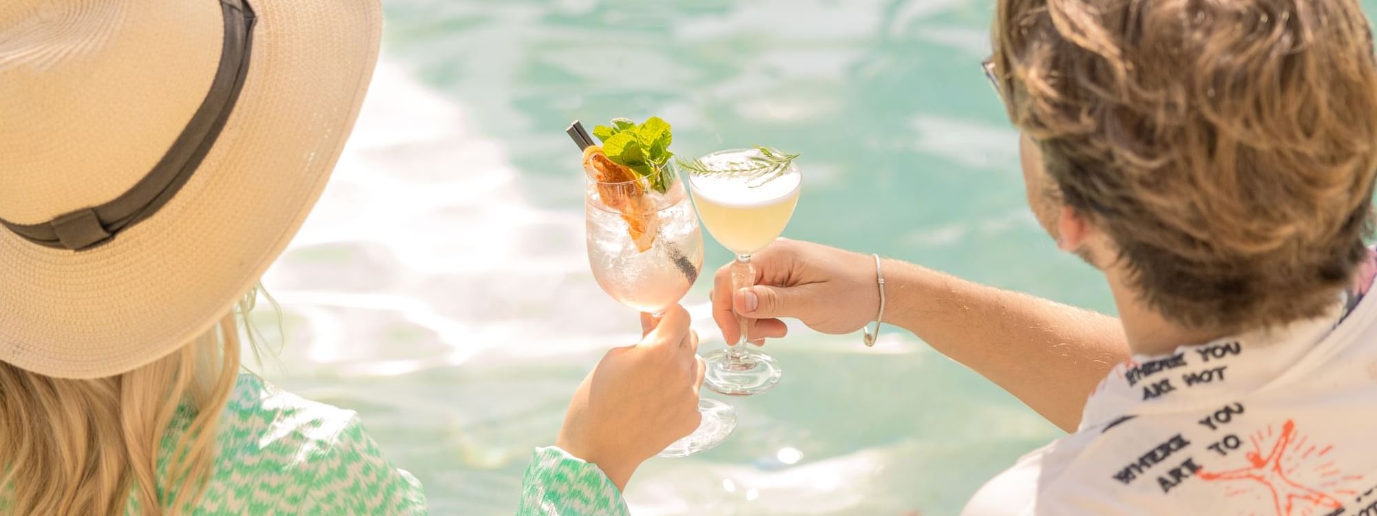 Couple toasting drinks by the pool at Pullman Port Douglas