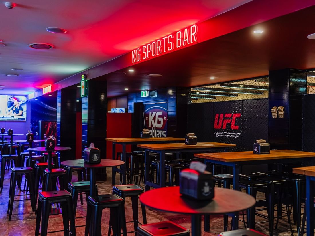 Vibrant KG Sport Bar interior with high-top tables and red neon signage at Mercure Brisbane King George Square