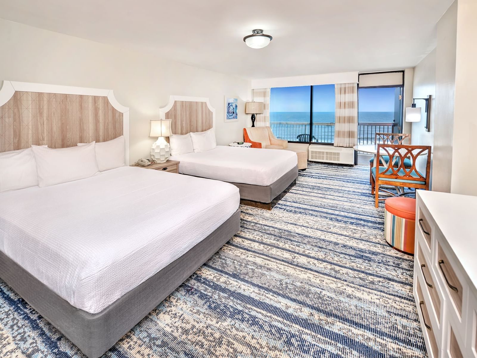 Two beds in a Bahama House hotel room in Daytona Beach with a kitchenette and tub.