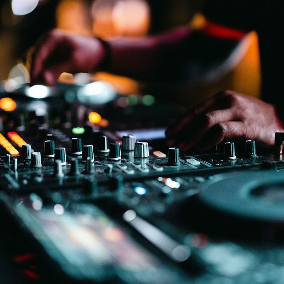 DJ's hands adjusting knobs on a mixer console at Falkensteiner Hotel Schladming