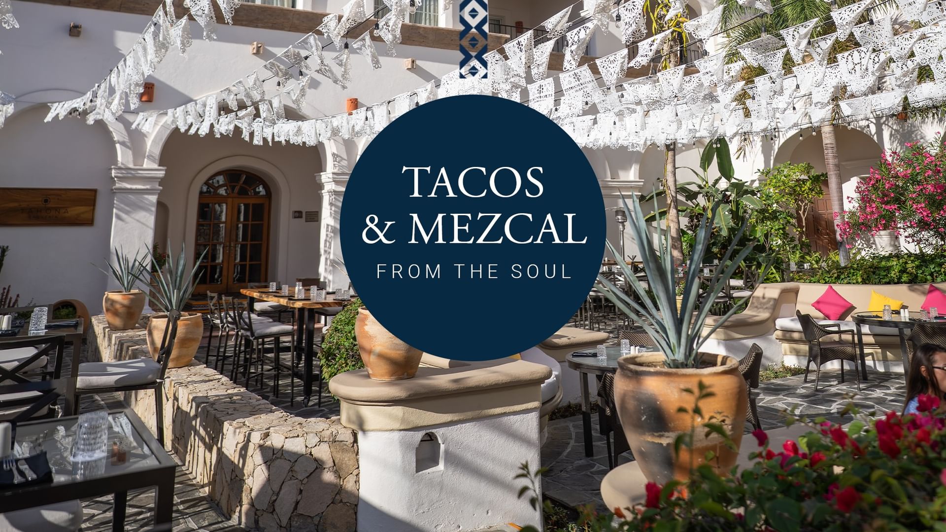 Patio decorado con jarrones y flores, mesas y sillas bajo luces, mostrando oferta de Tacos y Mezcales en Hacienda del Mar Los Cabos.