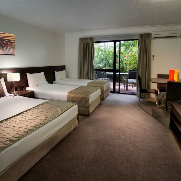 Three beds with workspace and balcony seating area in the Family Garden Room at Mercure Hotel Townsville