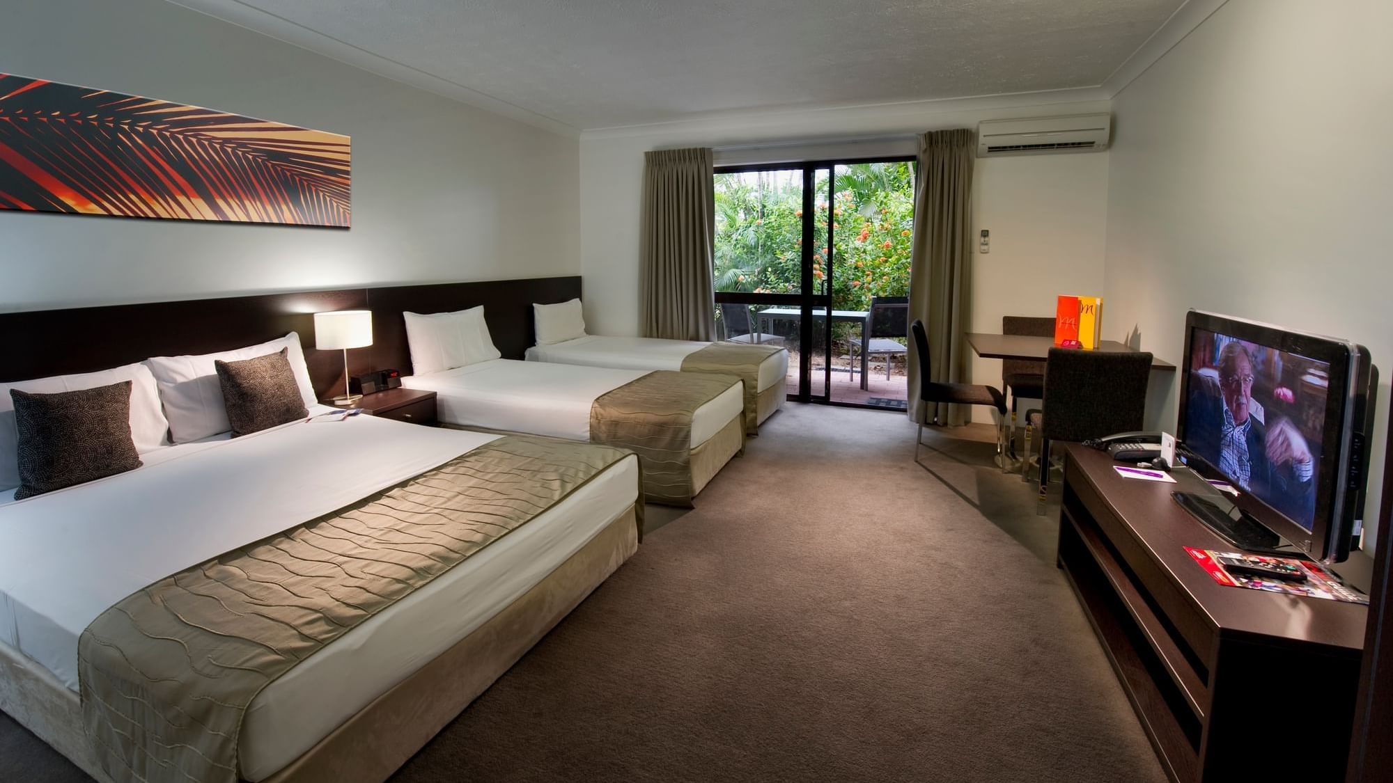 Three beds with workspace and balcony seating area in the Family Garden Room at Mercure Hotel Townsville