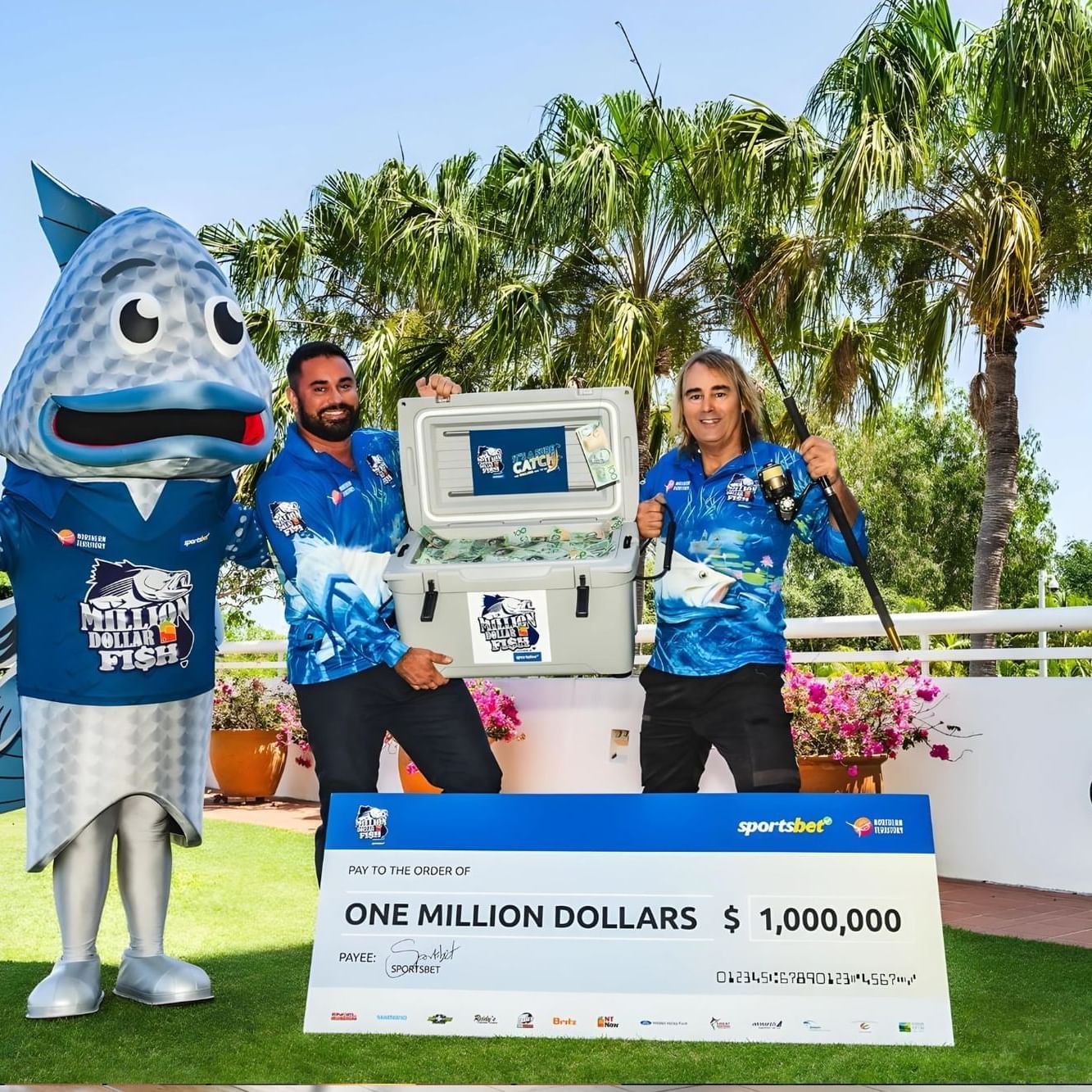 Two men in costumes holding a $1 million check for Fish competition near The Smith Hotel Darwin