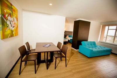 Twin Superior Dann Cali featuring a dining table, four chairs, a turquoise sofa, and colorful wall art at Dann Carlton Cali