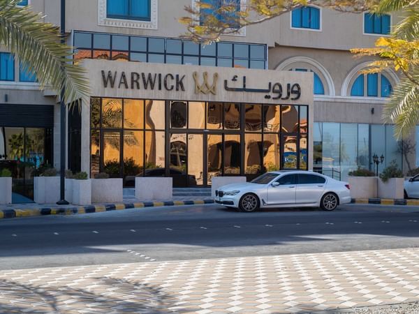 Exterior view of Warwick Hotel Al Jubail entrance with parked car on a sunny day
