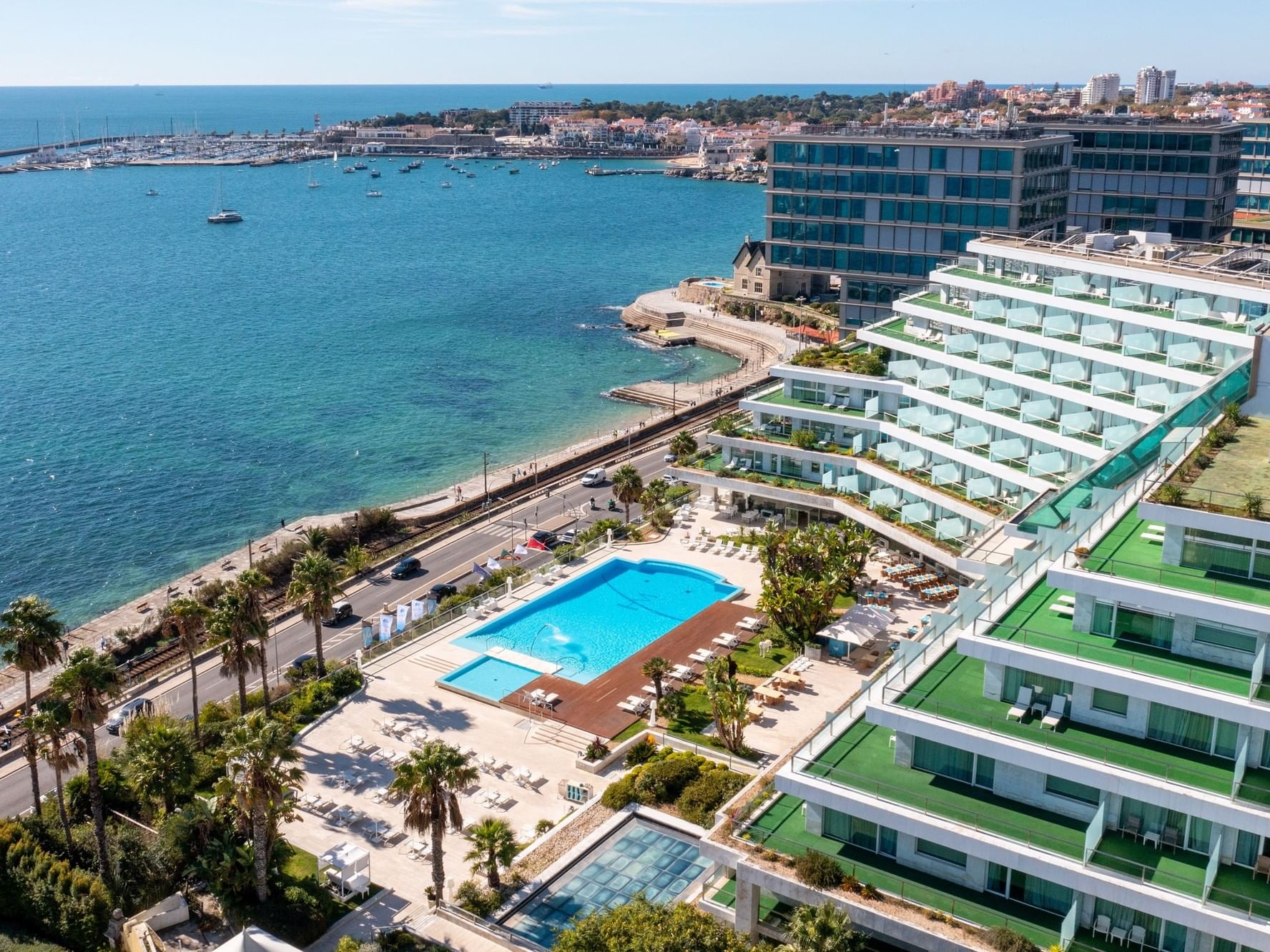 Vue aérienne du Hôtel Cascais Miragem avec piscine, immeubles et vue sur la mer.