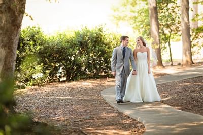 bride and groom walking along path through woods