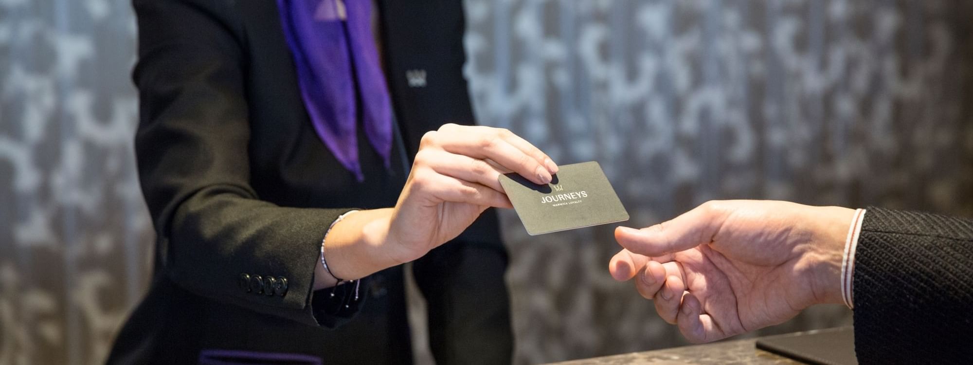 Close-up of receptionist giving a Warwick Journeys Membership Card at Roc e Fiori