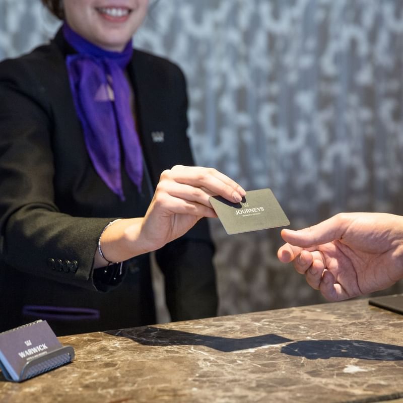 Close-up of receptionist giving a Warwick Journeys Membership Card at Roc e Fiori