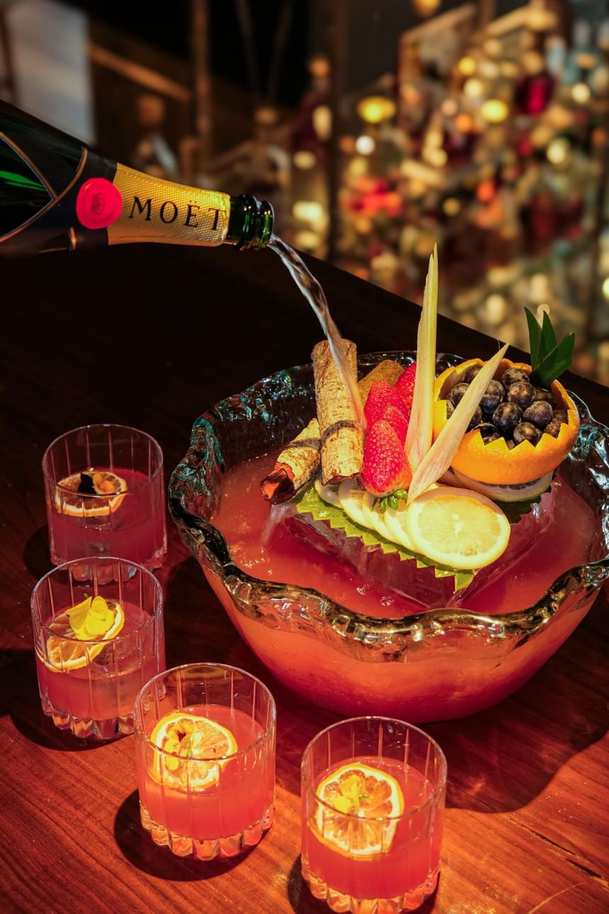 Punch bowl with fruit and spices, champagne pouring, and glasses on the table in 2 Lams Son at Park Hyatt Saigon