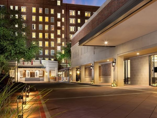 Elegant Warwick Melrose - Dallas entrance at dusk with warm exterior lighting and brick facade building