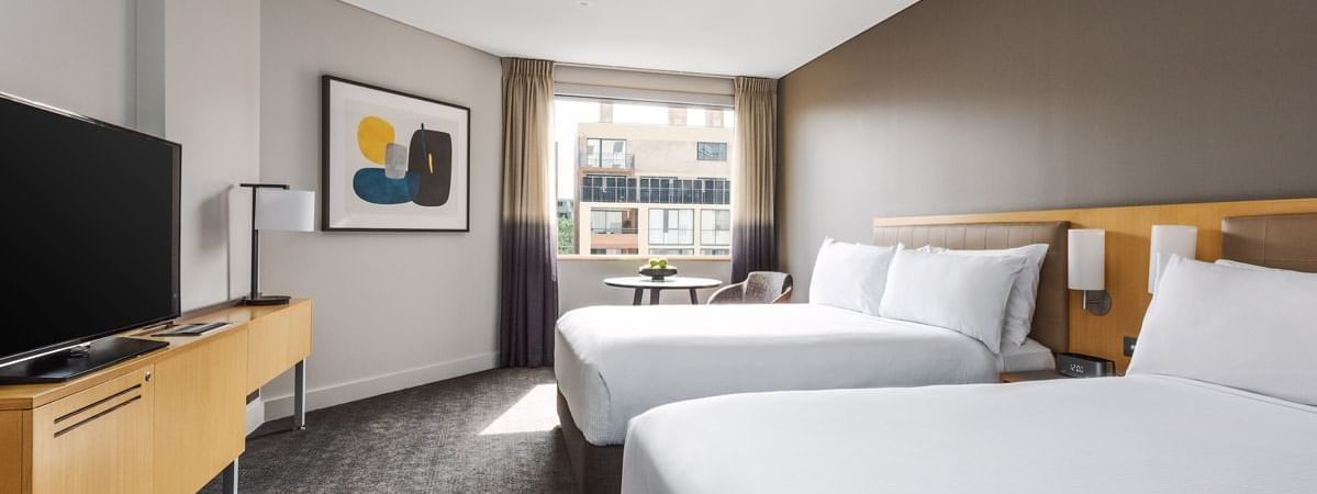 Two double beds with a TV and round table in Superior Room at Novotel Sydney on Darling Harbour