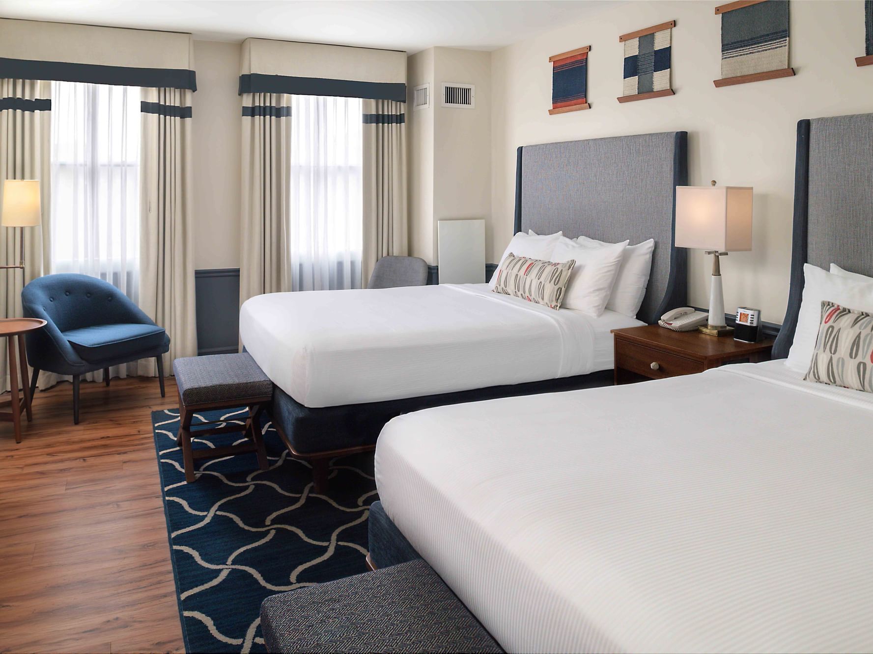 Two beds with cushioned headboards & ottomans in Deluxe Rooms at Portland Harbor Hotel