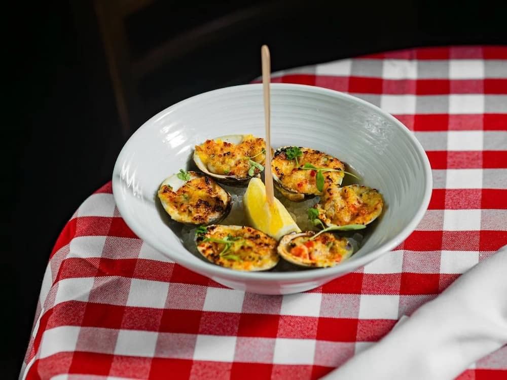 a white bowl of oysters on a red and white checkered tablecloth