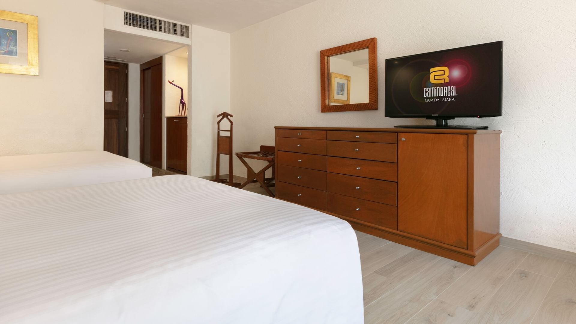 Habitación con dos camas dobles, televisor y mobiliario en Camino Real Guadalajara, Zapopan.