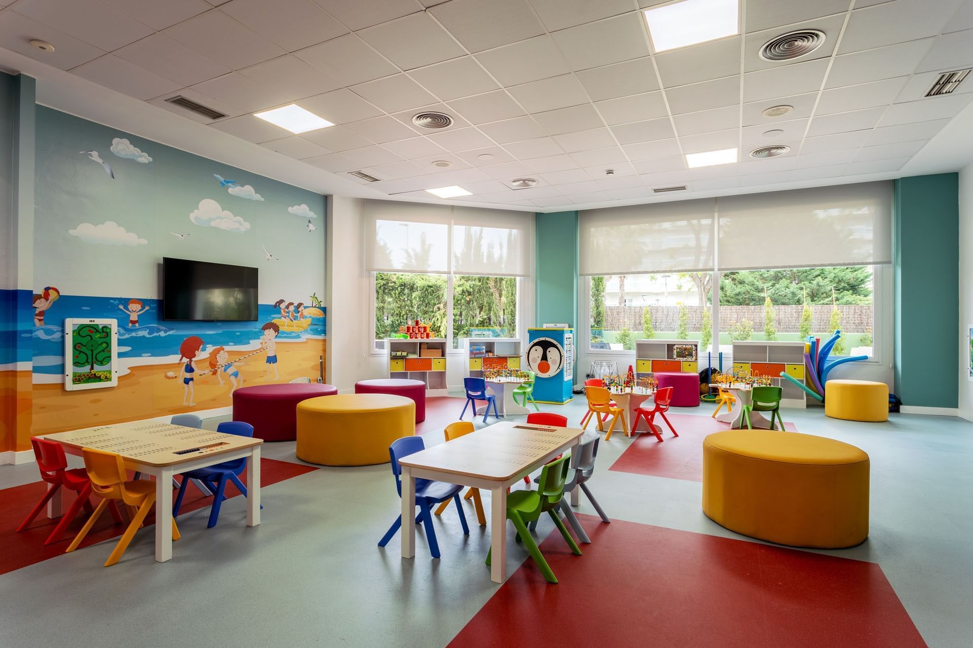 Área de juegos para niños con asientos organizados y paredes pintadas cerca de Ponient Hotels