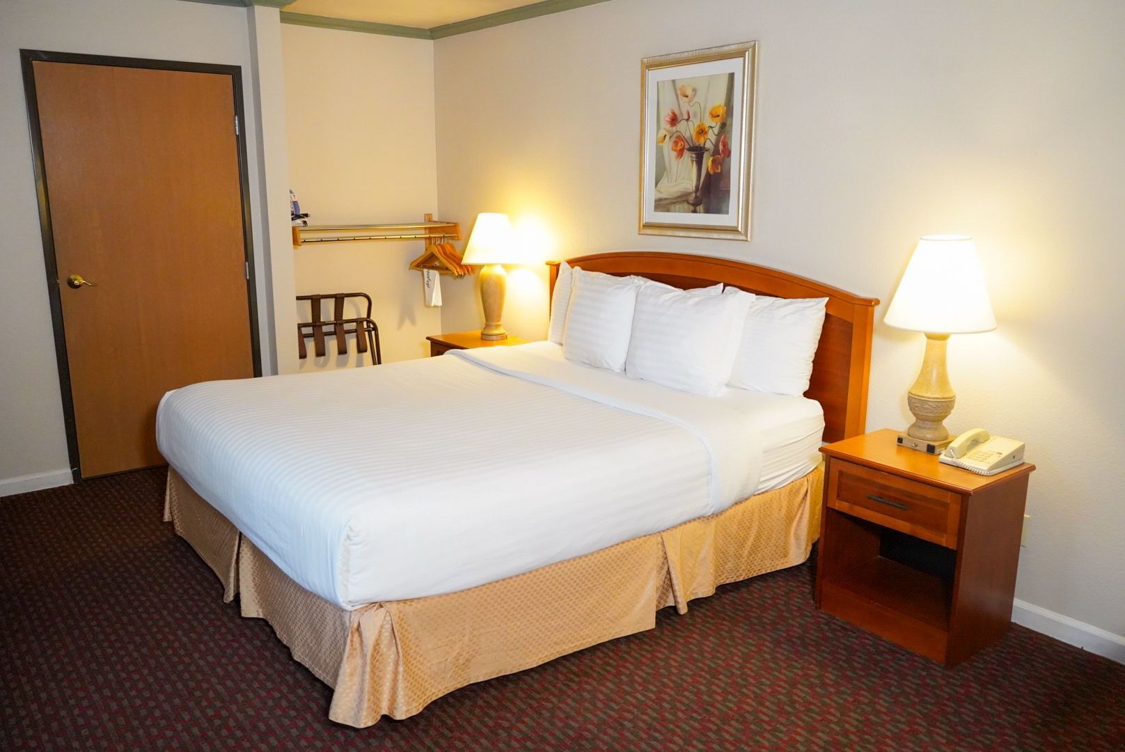 A standard hotel room with a double bed, two nightstands with lamps, and a door
