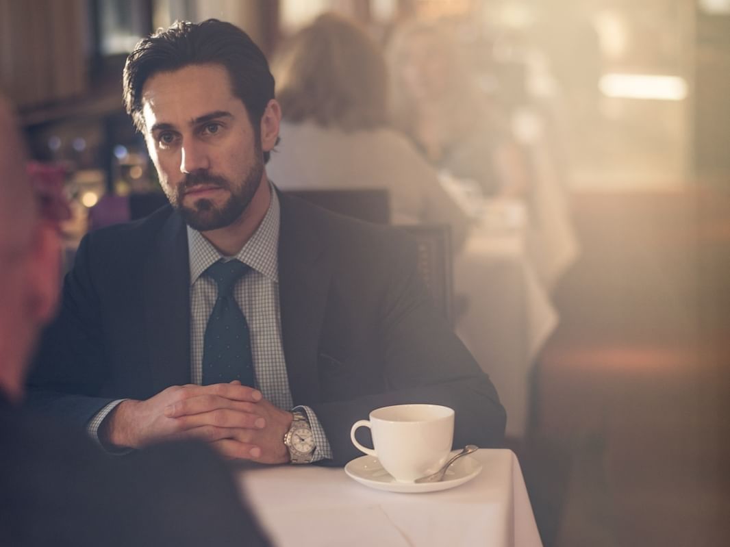 A man having a cup of coffee in a restaurant at Townsend Hotel