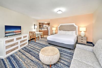 Ocean View King Kitchenette suite with a bed, couch, TV, dining set, dresser, and kitchen area at the Daytona Bahama House