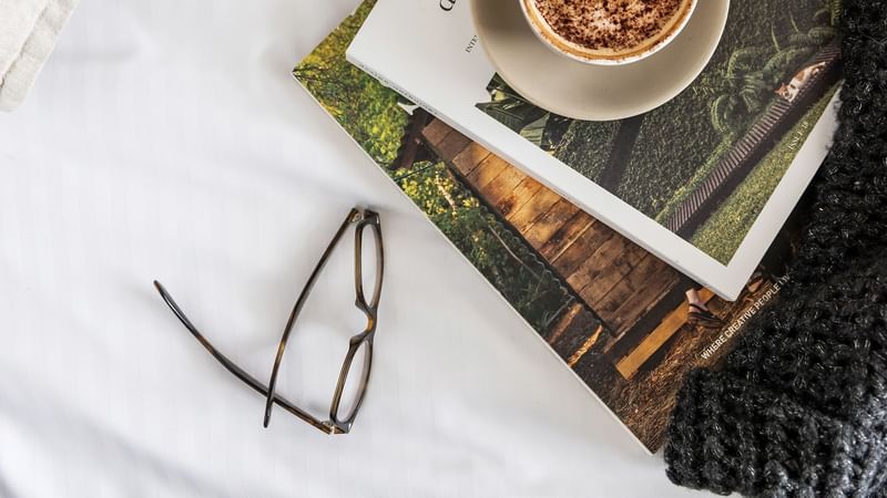 Magazines, a cup of latte and glasses placed on a table at Crown Hotels