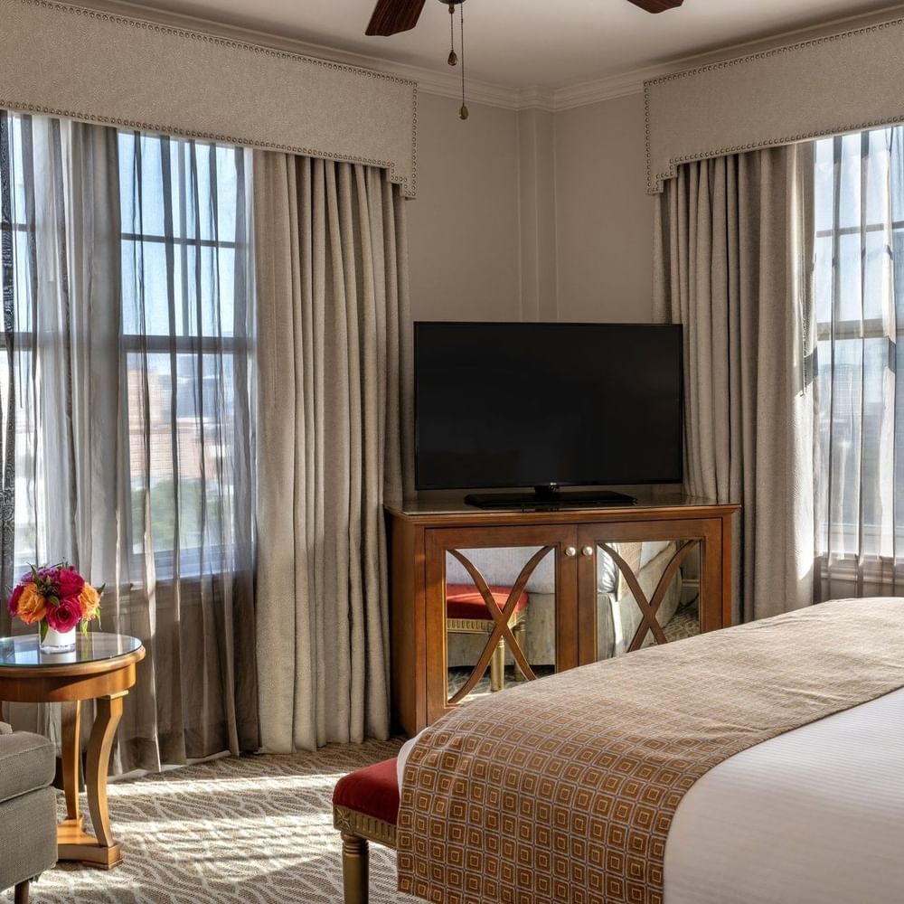 Elegant Corner King room with large bed, TV, and city view at Warwick Melrose Dallas.