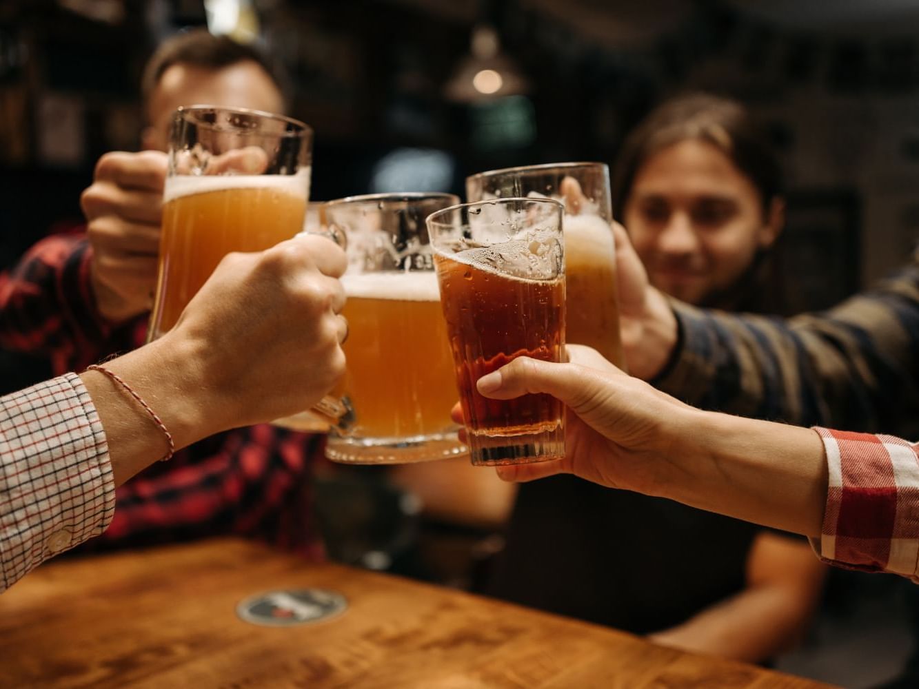 A group of people toasting with full beer mugs at Maine Beer Company near Ogunquit Collection