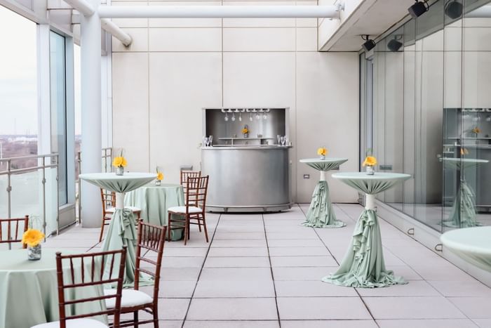 The  Cyprus outdoor terrace event space with tables draped in green fabric, and chairs at the Hotel Arista in Naperville, IL.