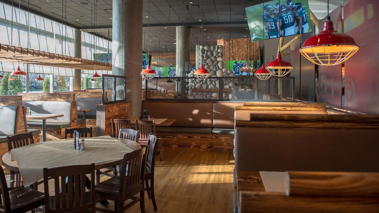 Restaurant interior with wooden booths, tables, and red pendant lights.