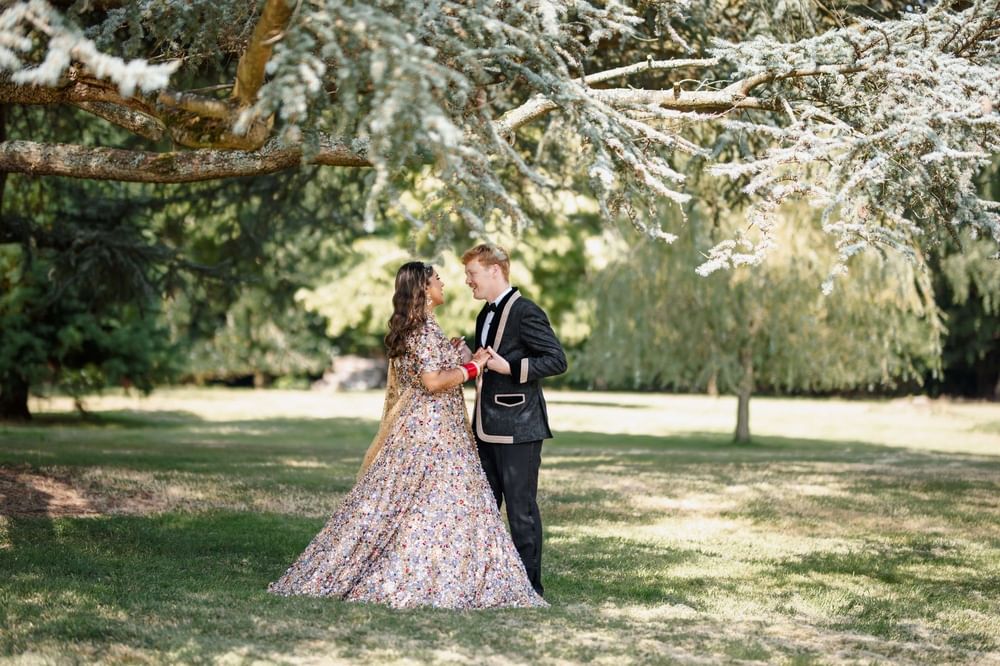 A couple together beneath the trees in the grounds at Easthampstead Park