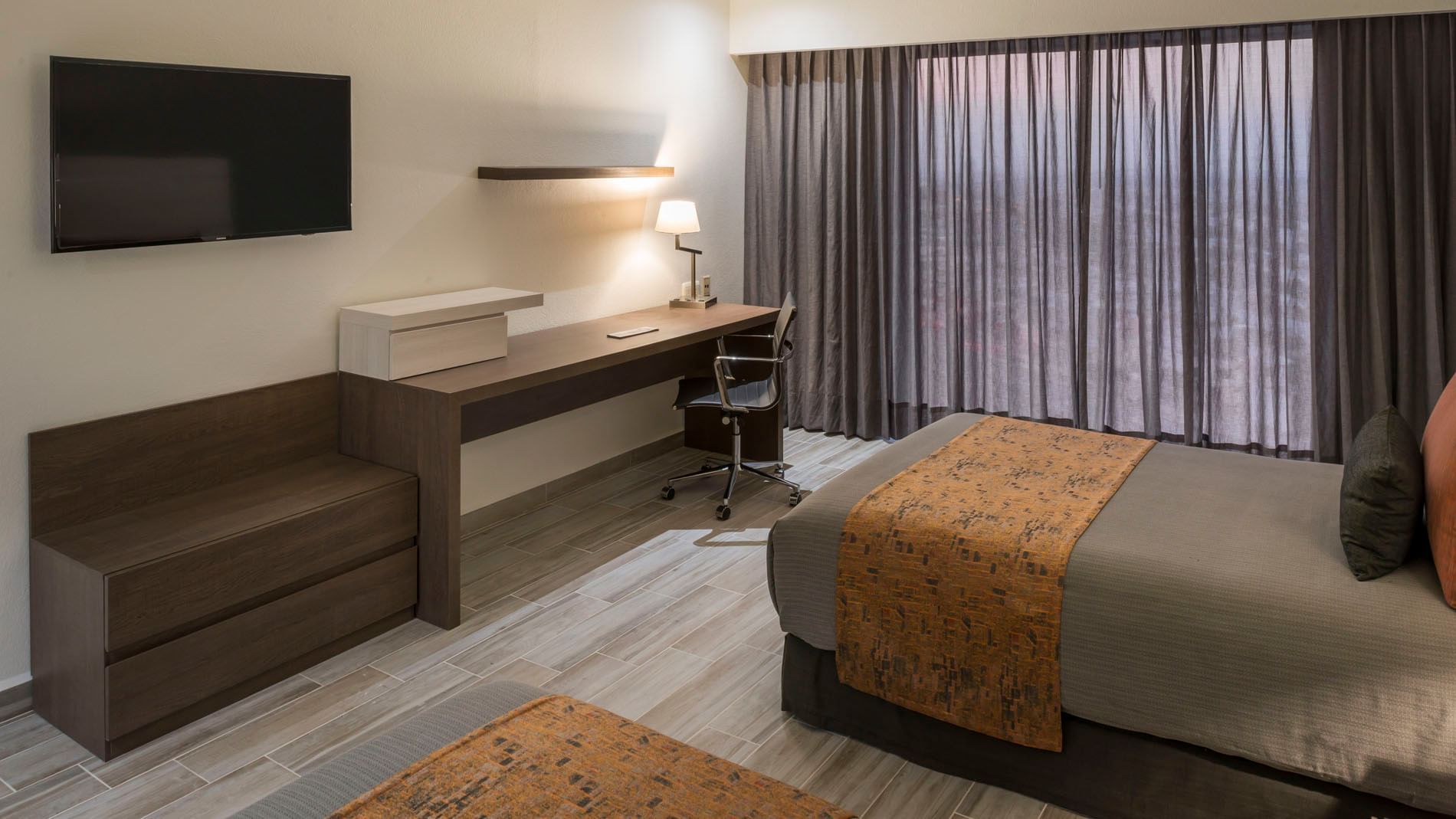 Wall-mounted TV and work desk facing the cozy beds in Deluxe Two Double Room at Real Inn San Luis Potosi