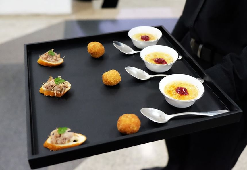 Close-up of a waiter in a black suit holding a tray of appetizers served at Park Hyatt Saigon