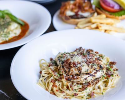 Spaghetti with meat served alongside lasagna, burger, and fries in the restaurant at The Ashbrook Hotel