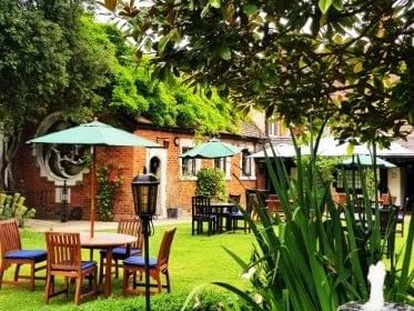 Lush garden at Marygreen Manor, featuring tables and chairs under green umbrellas for a relaxing outdoor setting