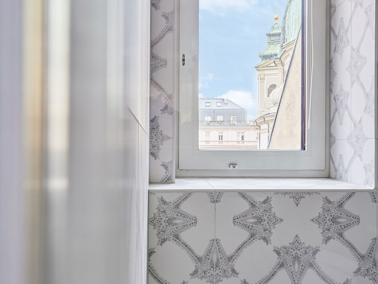 White tile wall with star pattern, small window with cityscape view, and white frame.